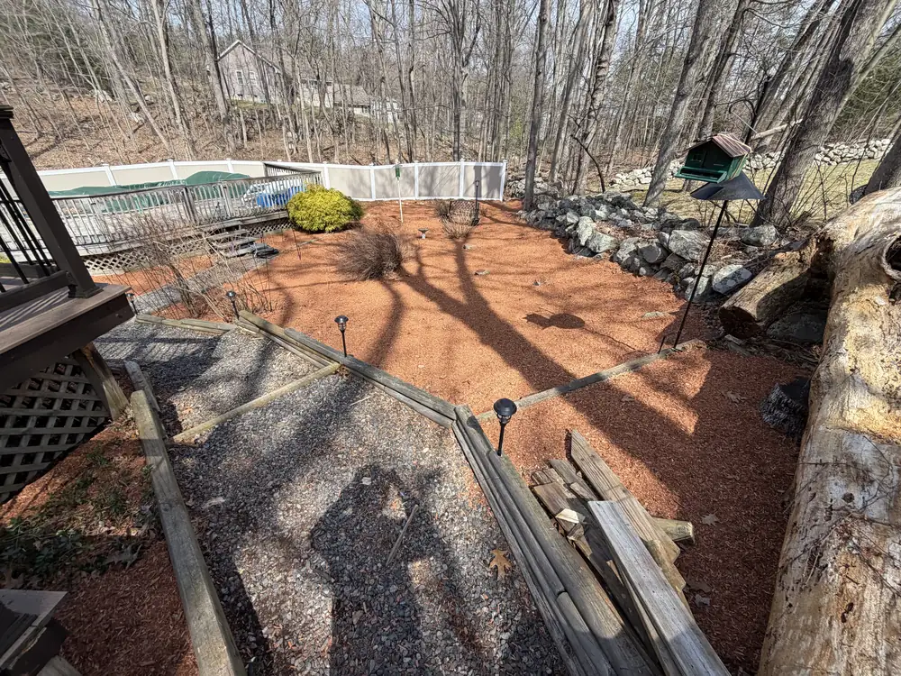 Red mulch landscape beds around backyard trees in Shrewsbury MA